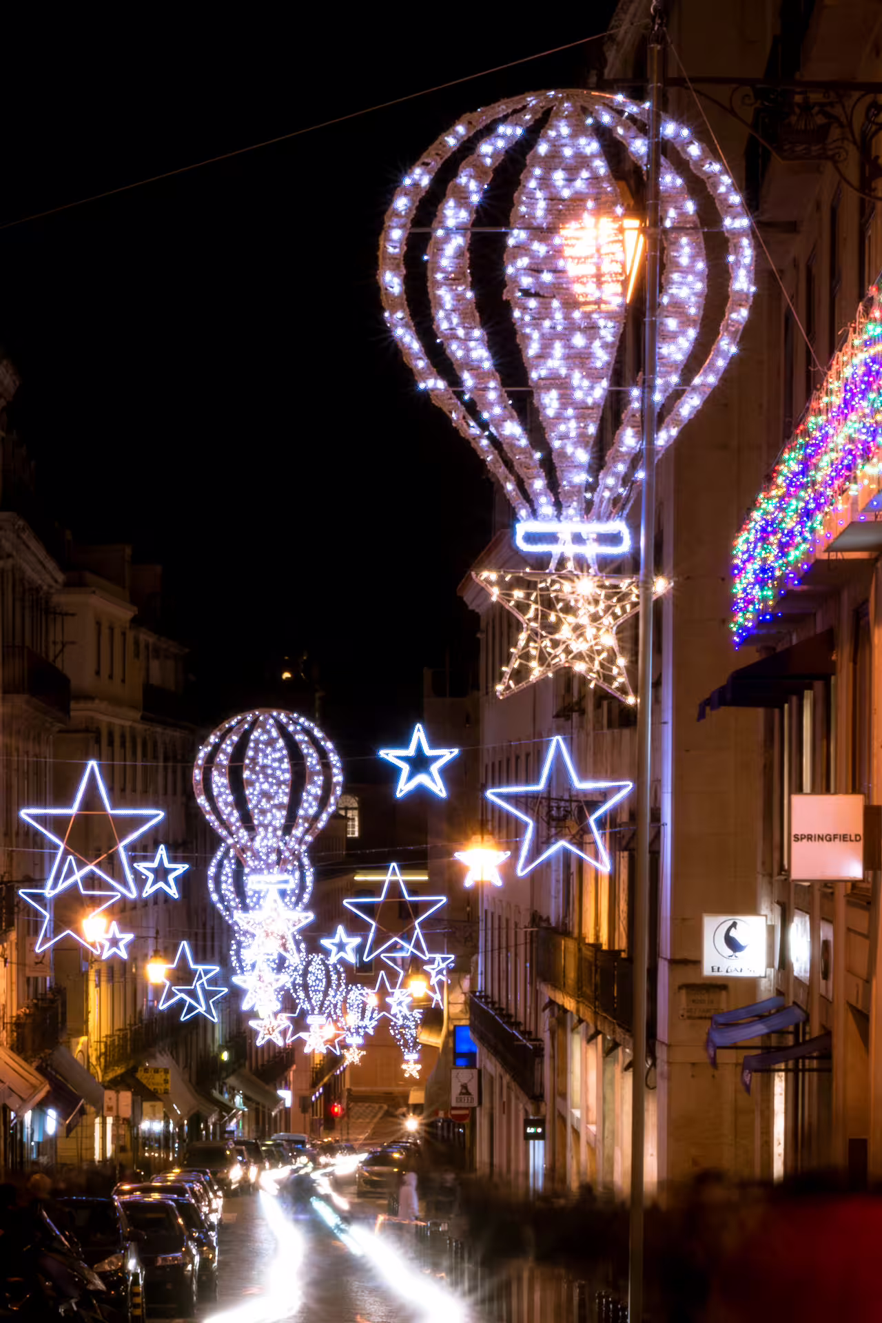 Lisbon street illuminated with festive Christmas lights featuring hot air balloons and stars during a private night photo walk.