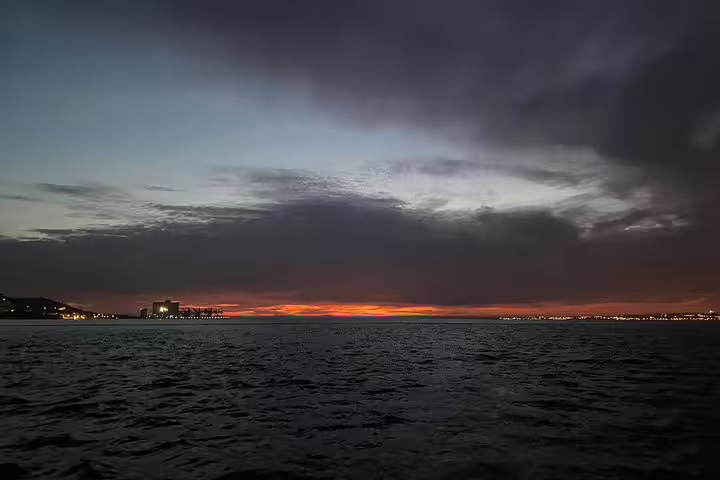 Vibrant sunset over Lisbon's waterfront captured during a serene night sailing tour on the Tagus River.