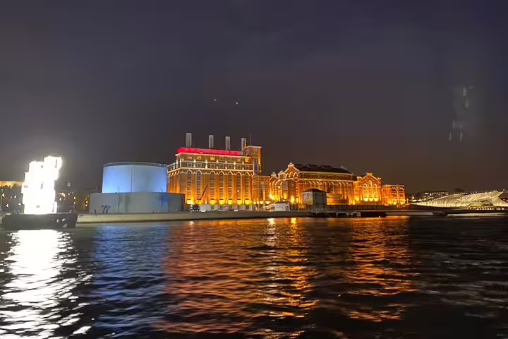 Night view of Lisbon's illuminated waterfront from a sailing tour, showcasing vibrant city lights reflecting on the Tagus River.