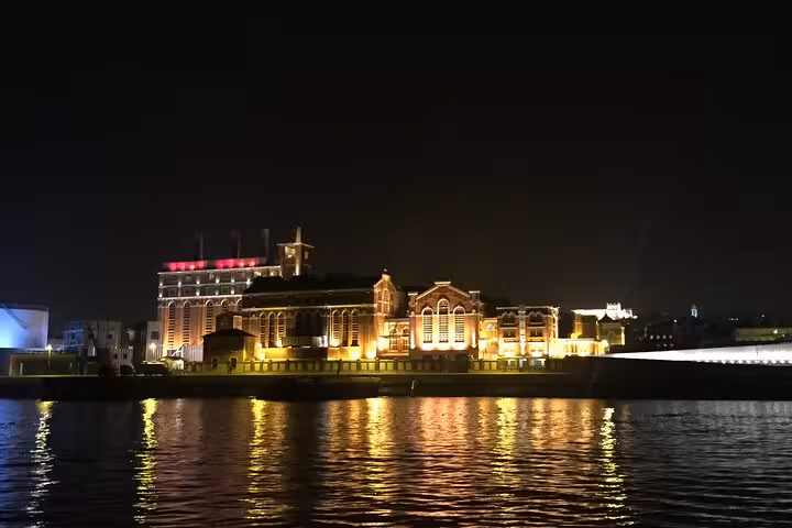 Night sailing tour Lisbon passing illuminated riverside buildings, Tagus River reflections, drinks included