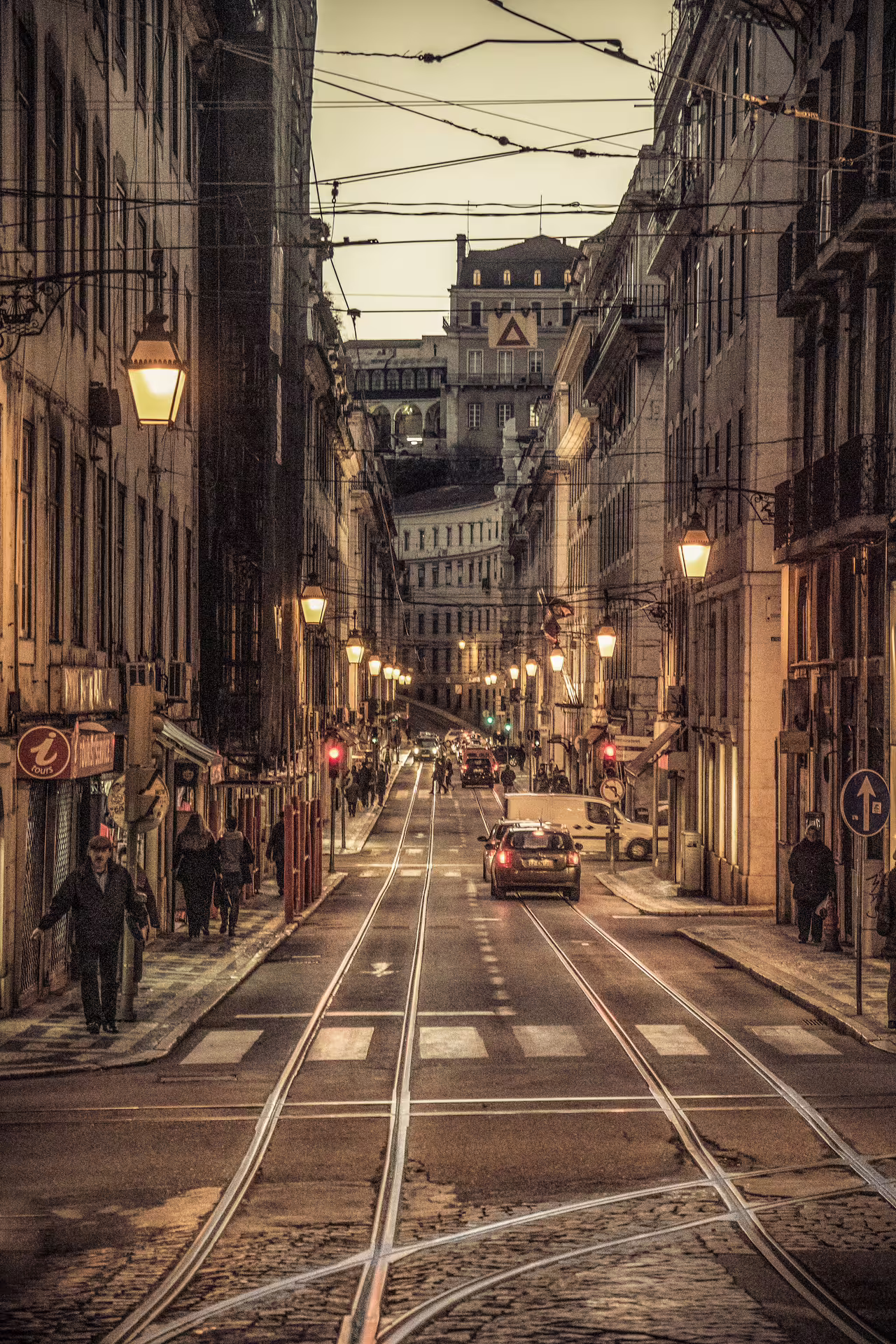 Evening view of a charming Lisbon street with tram tracks, historic architecture, and glowing streetlights during a sunset photo walk.