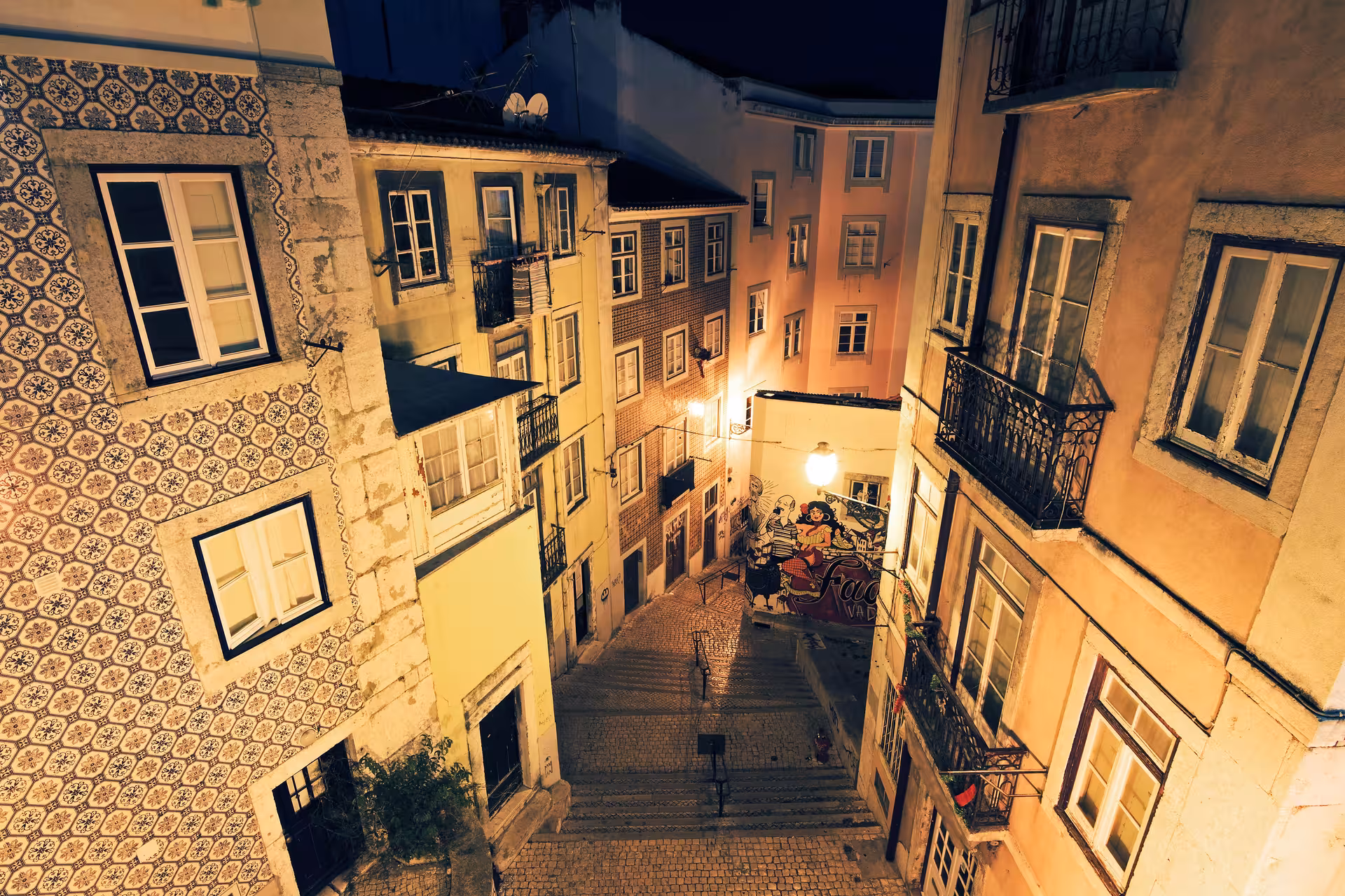 Charming narrow street in Lisbon illuminated at night, highlighting traditional Portuguese architecture.