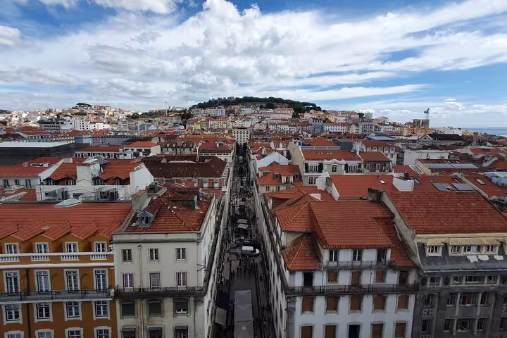 Aerial view of Lisbon's historic old town with red-tiled rooftops and vibrant architecture under a blue sky, perfect for a private full-day tour.