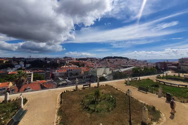 Panoramic view of Lisbon's old town under a vibrant sky, highlighting historic architecture and the scenic cityscape on a full-day tour.