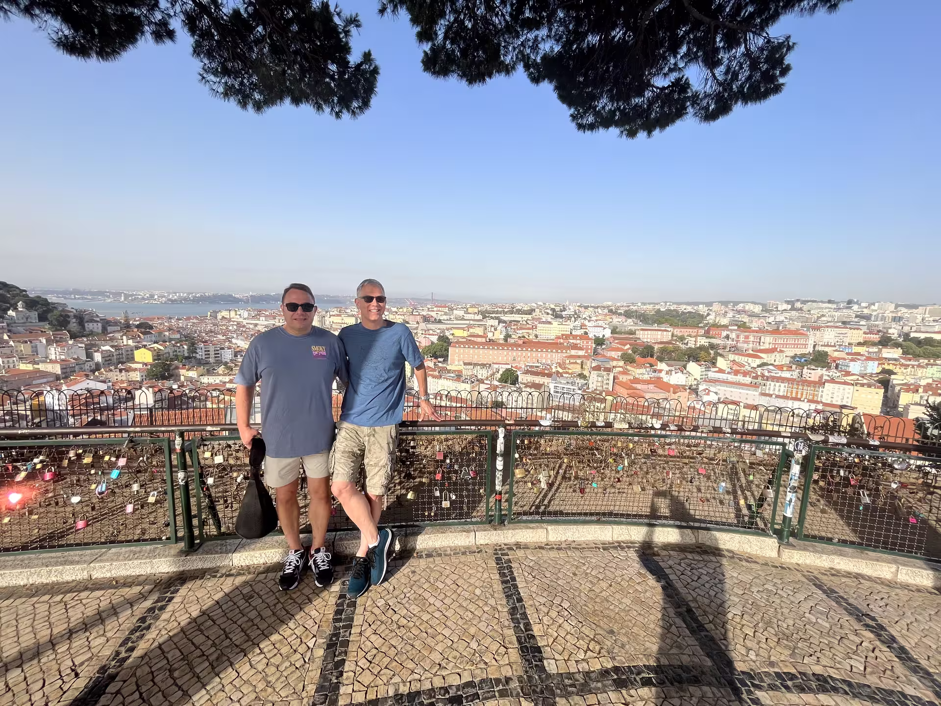 Tourists enjoy panoramic views of Lisbon from a scenic overlook, highlighting the city's beauty on a sunny day.