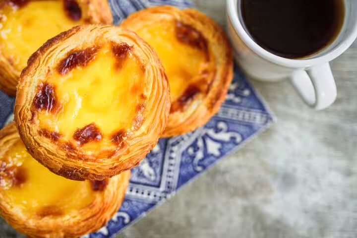 Portuguese custard tarts (pastéis de nata) with a cup of coffee, highlighting Lisbon's culinary delights on a private tour.