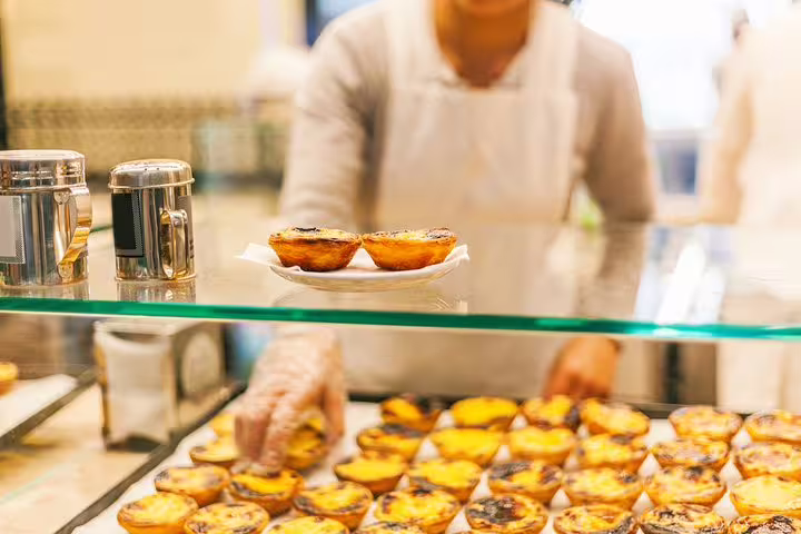 A local vendor serves fresh pastéis de nata in Lisbon, a highlight of the private walking tour exploring the city's culinary secrets.