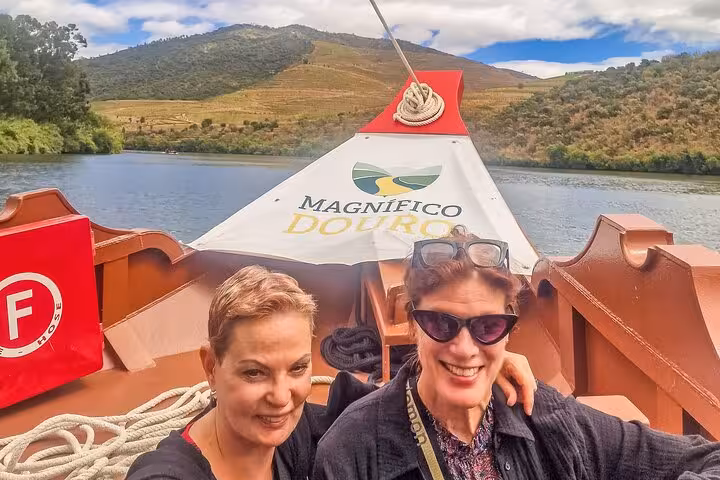 Guests on a Douro River boat during Lisbon to Porto ride, enjoying scenic valley views and wine tour