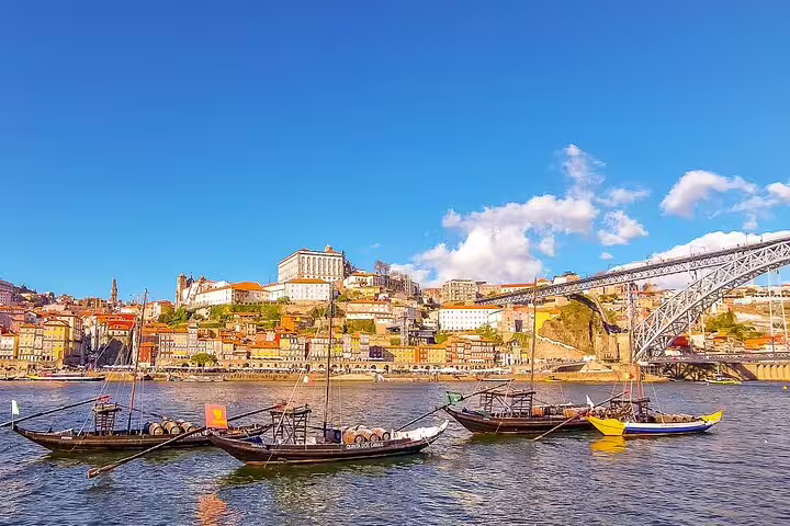 Traditional boats on the Douro River with Porto's colorful Ribeira district and iconic bridge, perfect for a scenic 3-day tour.