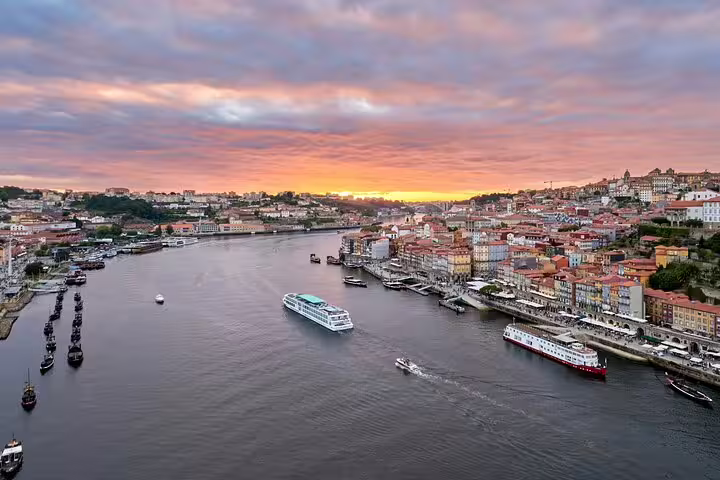 Scenic sunset view of Porto's Douro River with boats cruising, perfect for Lisbon to Porto private transfer tours.