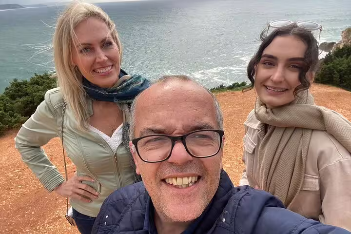 Smiling travelers enjoying scenic ocean views during a private transfer from Lisbon to Porto with scenic stops.