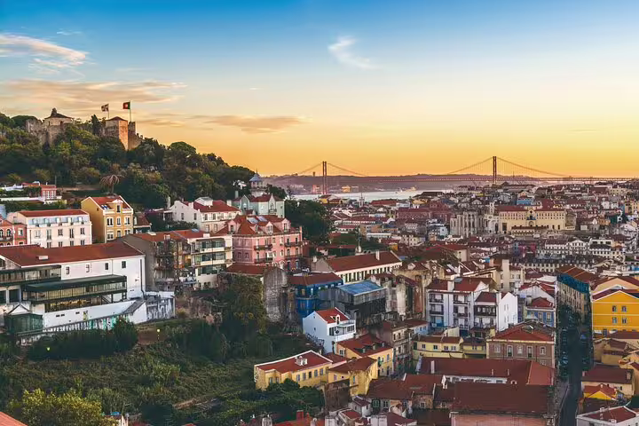 Scenic view of Lisbon's colorful rooftops and historic landmarks at sunset, ideal for a Lisbon to Porto private journey.