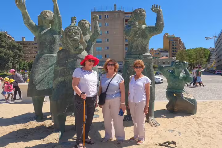 Tourists enjoying a sunny day by unique statues in a lively Lisbon square, ideal for cultural exploration on the way to Porto.