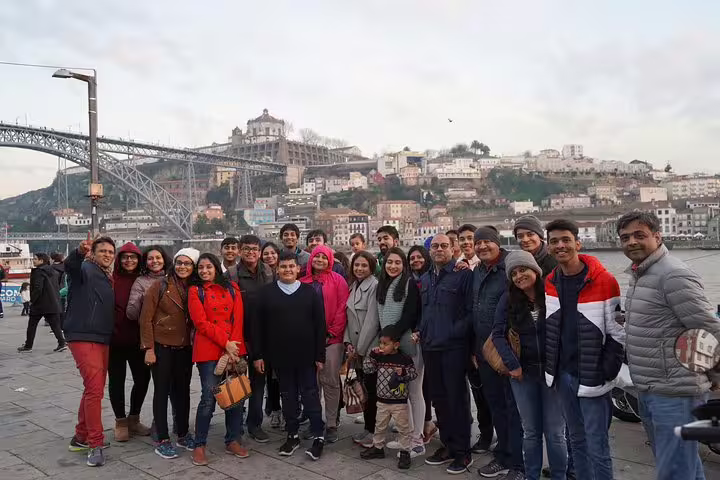Group of tourists enjoying a scenic view of Porto with iconic Luís I Bridge during a Lisbon to Porto transfer tour with stops.