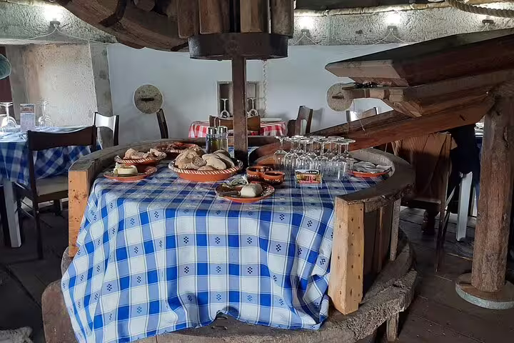 Traditional Portuguese dining setup in Lisbon restaurant with rustic decor, featuring local food and wine on a checkered tablecloth.