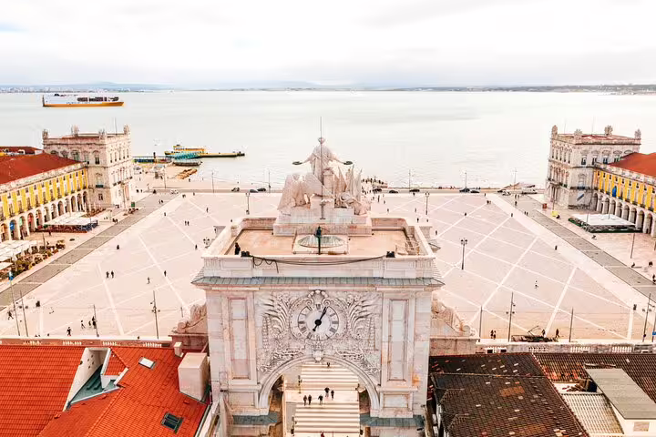 Aerial view of Lisbon's iconic Praça do Comércio and Rua Augusta Arch, showcasing stunning architecture and Tagus River backdrop.