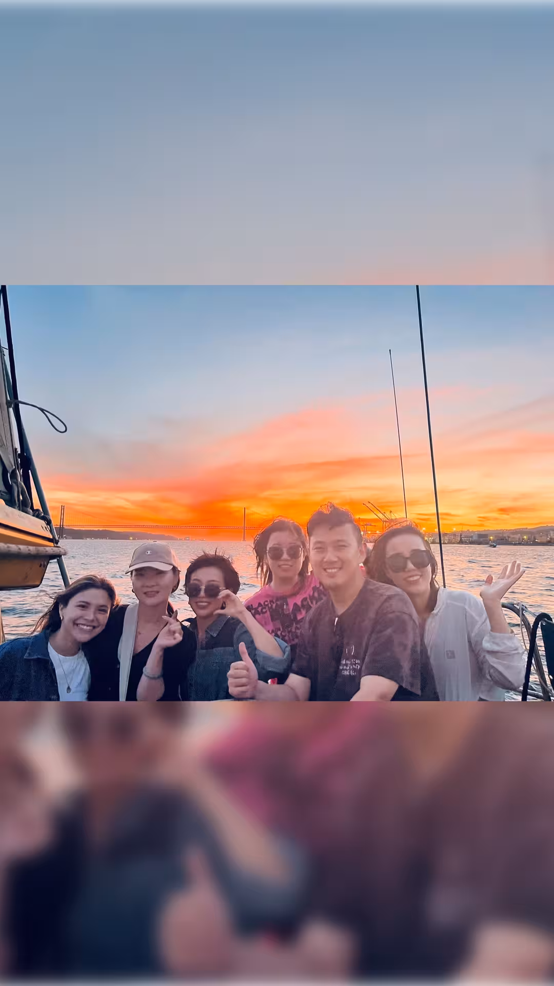 Friends enjoying a Lisbon private boat tour at sunset on the Tagus River with 25 de Abril Bridge views