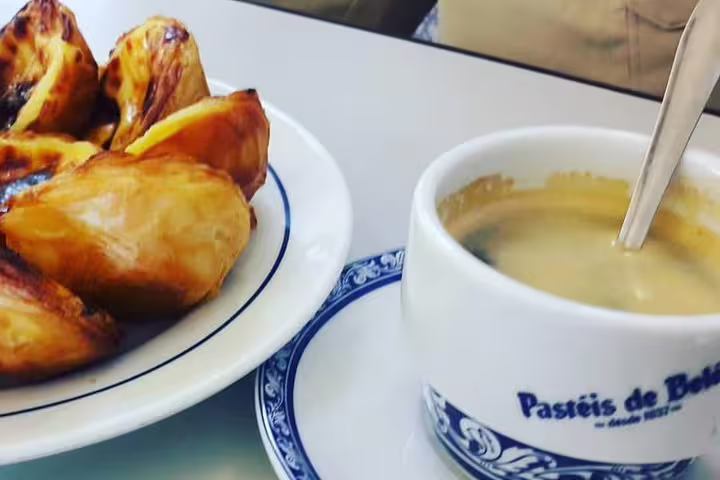 Enjoy a Lisbon half-day private tour with custom stops, featuring a premium vehicle and savoring authentic pastéis de nata and coffee.