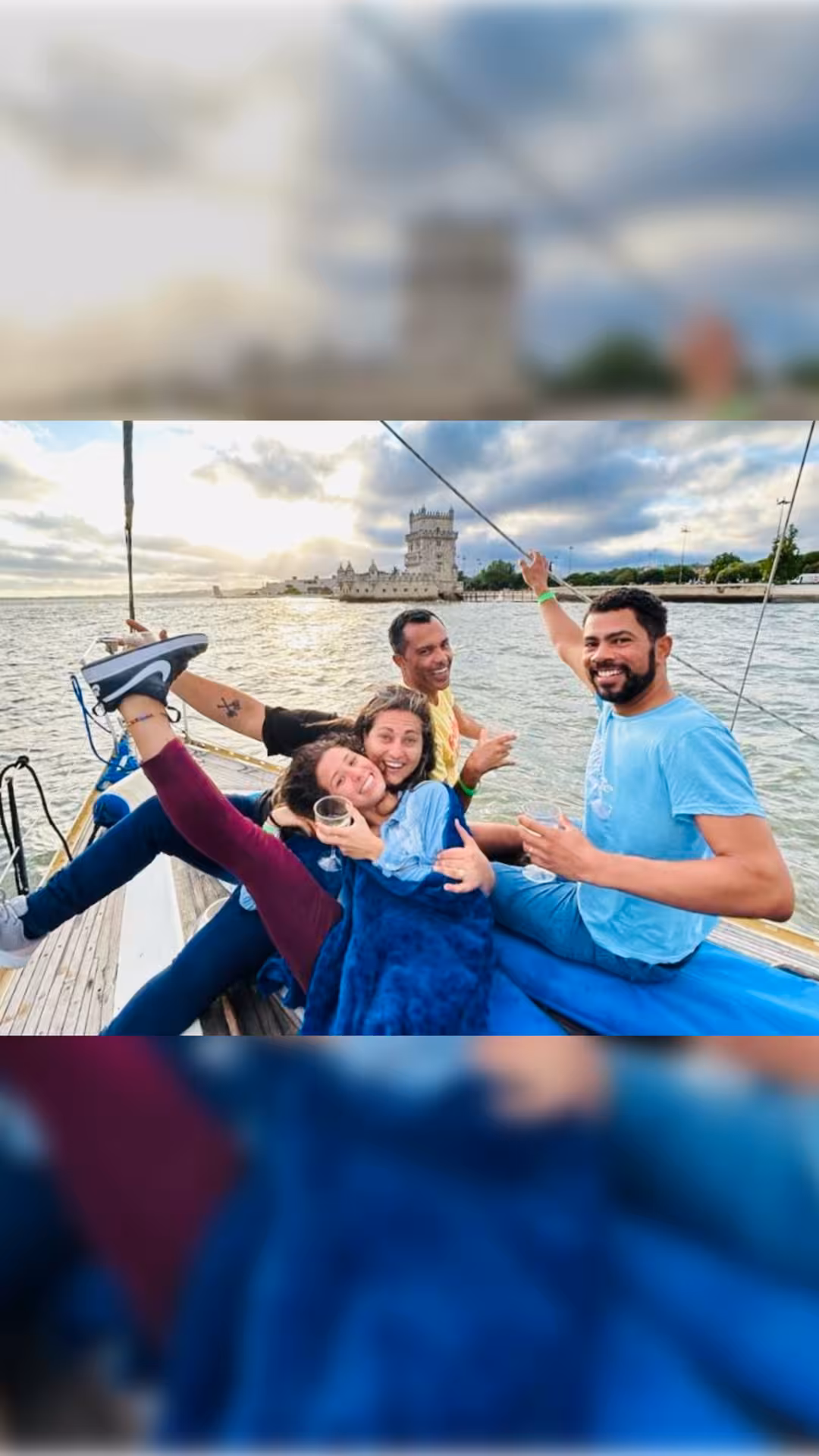 Group relaxing on a Lisbon private sailboat tour near Belém Tower on the Tagus River with drinks and smiles