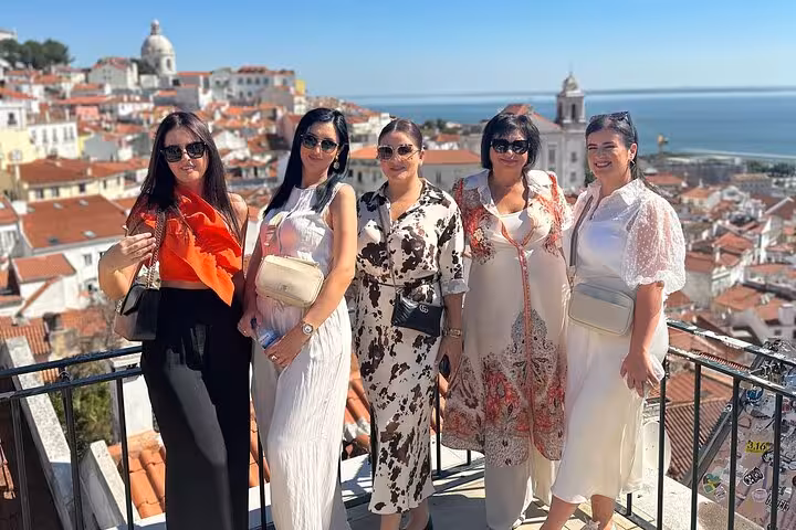 Group of five women enjoying a scenic view of Lisbon's historic Alfama district and Tagus River on a private tour.