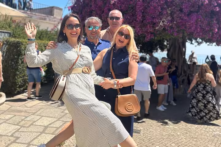 Smiling visitors posing under vibrant bougainvillea in sunny Lisbon on a private sightseeing tour.