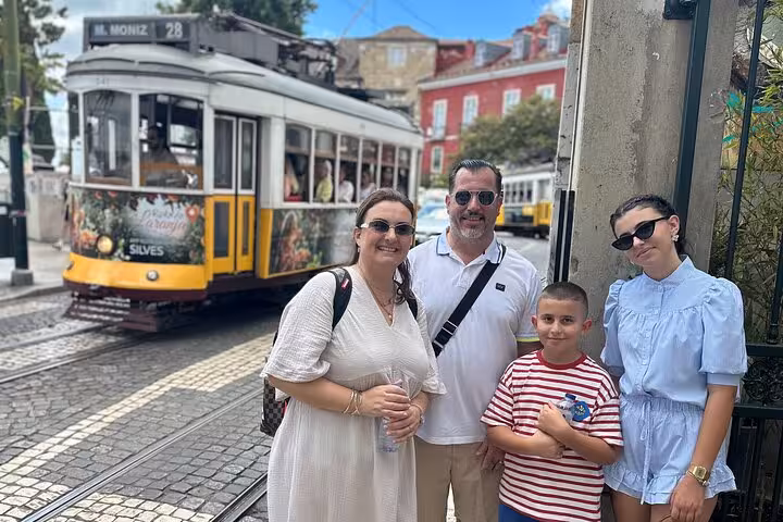 Family smiling with a classic Lisbon tram in the background during a private city tour.