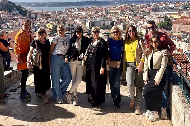 Group of tourists enjoying a panoramic view of Lisbon's colorful cityscape during a private tour.