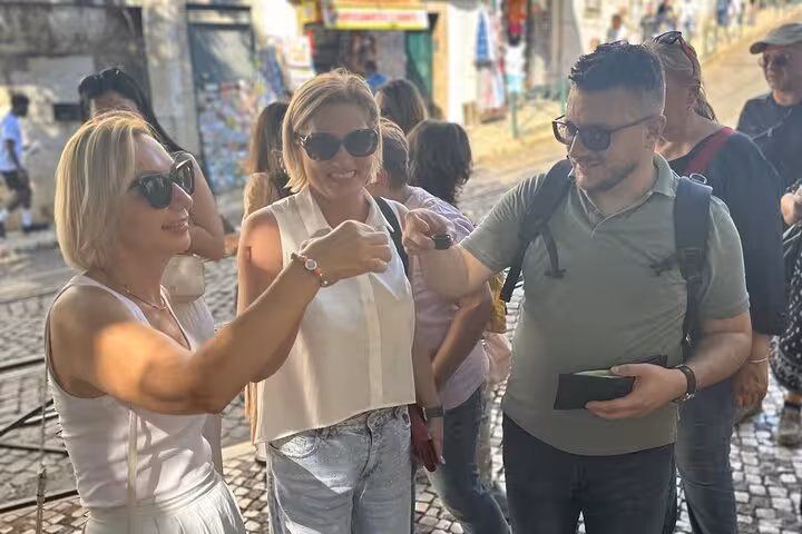 Group of tourists enjoying a toast on a charming street during a Lisbon private tour.
