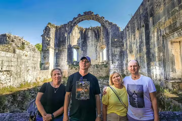 Tourists explore ancient ruins on a private full-day tour from Lisbon to Óbidos, Nazaré, Alcobaça, Batalha, and Fátima.