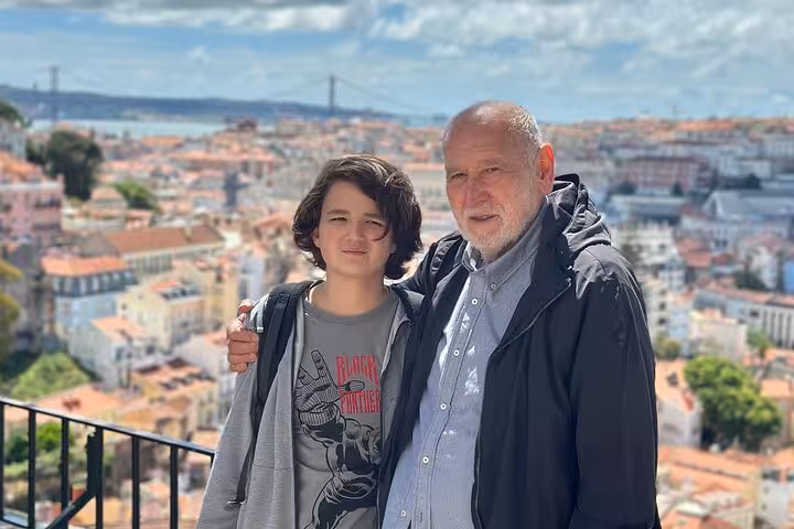 Visitors enjoying a scenic view of Lisbon's rooftops and the 25 de Abril Bridge on a private city tour.