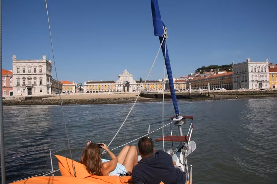Couple relaxing on sailboat on the Tagus River with Lisbon Commerce Square views on a romantic luxury cruise