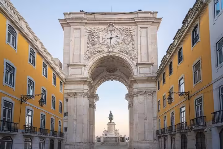 View of Lisbon's Rua Augusta Arch, capturing its intricate details and yellow surrounding buildings at sunset.