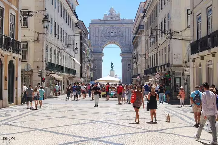 People strolling along Lisbon's historic Rua Augusta, featuring the iconic Arco da Rua Augusta and vibrant city life.