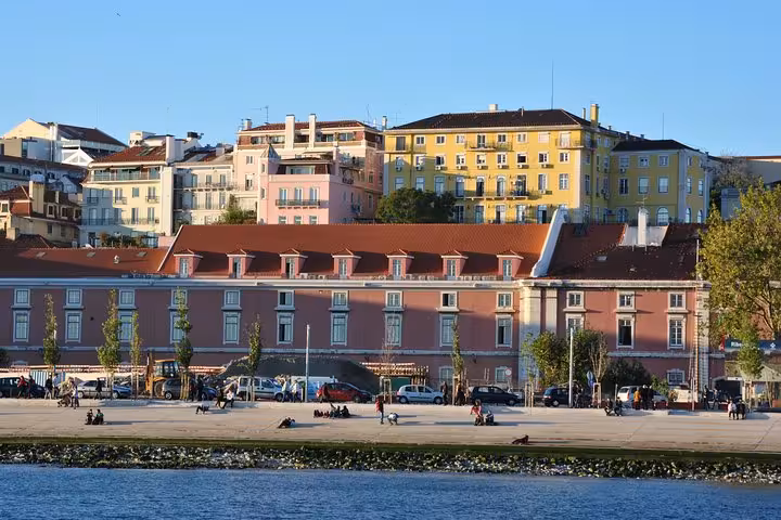 Ribeira das Naus waterfront and colorful Lisbon old town buildings seen from Tagus River sailing cruise with drink