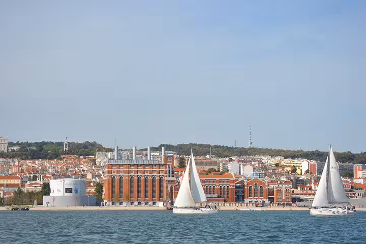 Small group Lisbon sailing cruise on the Tagus River with sailboats passing Praça do Comércio waterfront