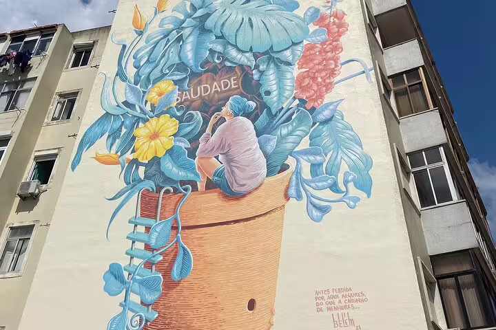 Vibrant Lisbon mural depicting 'Saudade' with lush foliage and a contemplative figure, highlighting the city's artistic flair.