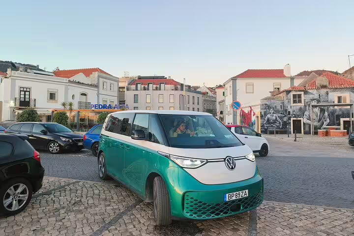 Electric ID Buzz parked in a picturesque Lisbon square, ready for a stylish trip to Sesimbra with lunch included.