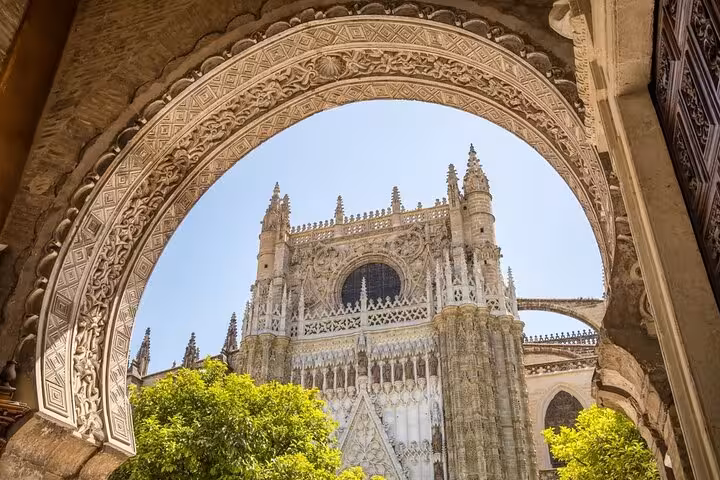Intricate Gothic architecture of Seville Cathedral framed by ornate archway, capturing historical elegance and craftsmanship.
