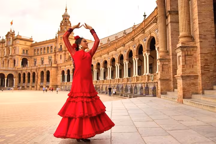 Flamenco dancer in vibrant red dress performing at Plaza de España, Seville, on a private transfer tour.