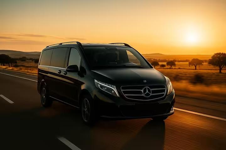 Luxurious Mercedes van on a scenic road at sunset, ideal for Lisbon to Seville private transfer journeys.