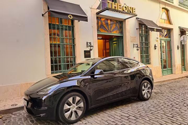 Sleek black car parked on cobblestone street outside luxury hotel, perfect for the Lisbon to Seville private journey.
