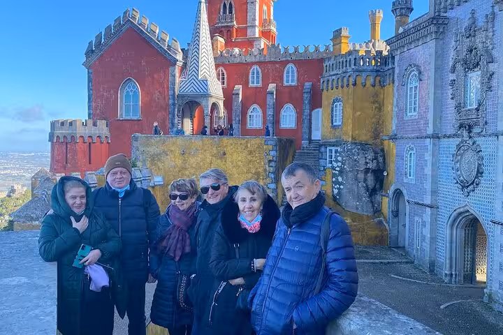 Group of tourists enjoying the vibrant architecture of Pena Palace on a sunny Lisbon to Sintra guided tour.