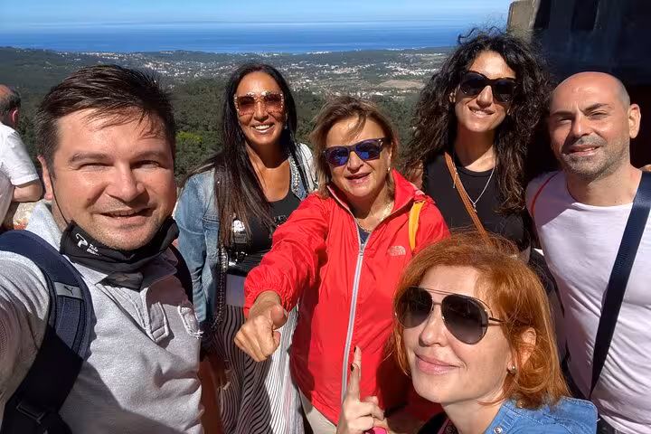 Group enjoying scenic views on Lisbon to Sintra guided tour with Pena Palace backdrop.