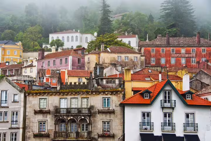 Colorful historic buildings nestled in the misty hills of Sintra, Portugal, showcasing the charm of a full-day tour from Lisbon.