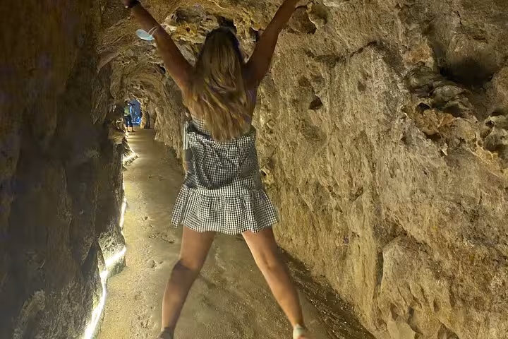Visitor exploring a dimly lit cave tunnel in Sintra, showcasing the adventurous side of the guided tour experience.