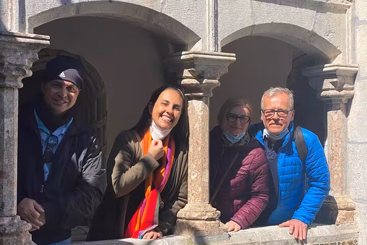 Happy travelers pose at historic site during Lisbon to Sintra 8pax guided tour.