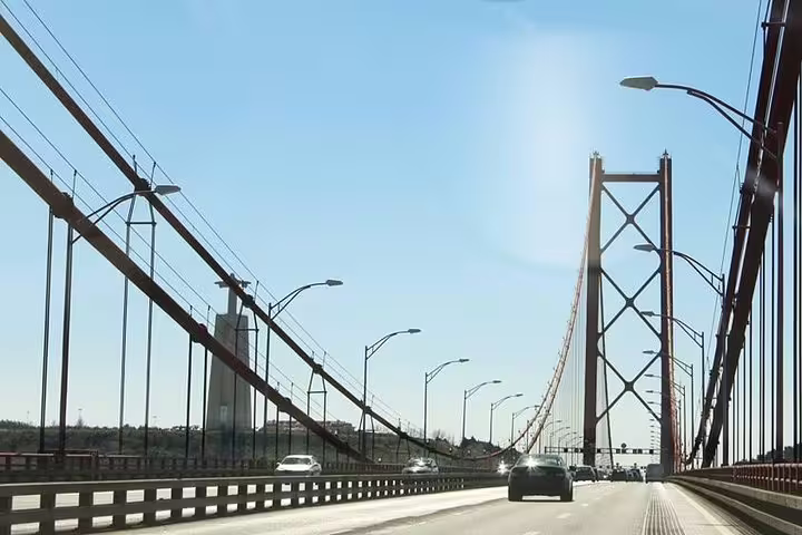 View from the 25 de Abril Bridge on a sunny day during a private tour of Lisbon and Sintra, highlighting iconic architecture.