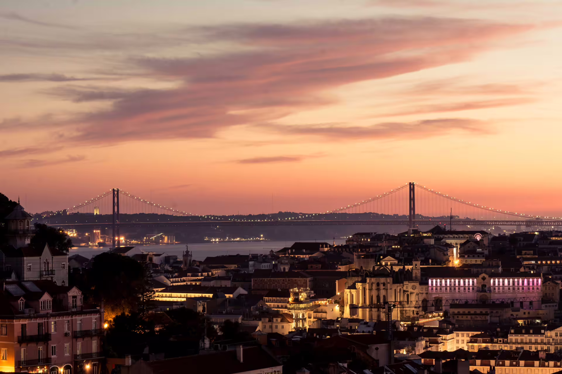 Lisbon skyline at sunset with illuminated bridge, perfect for capturing Christmas lights on a private photo walk tour.