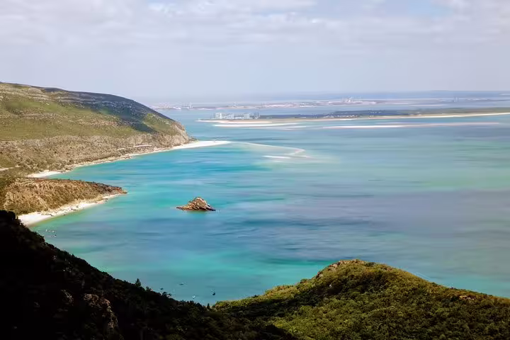 Scenic view of Lisbon's southern coast with turquoise waters and lush hills, perfect for wine tours and sightseeing adventures.