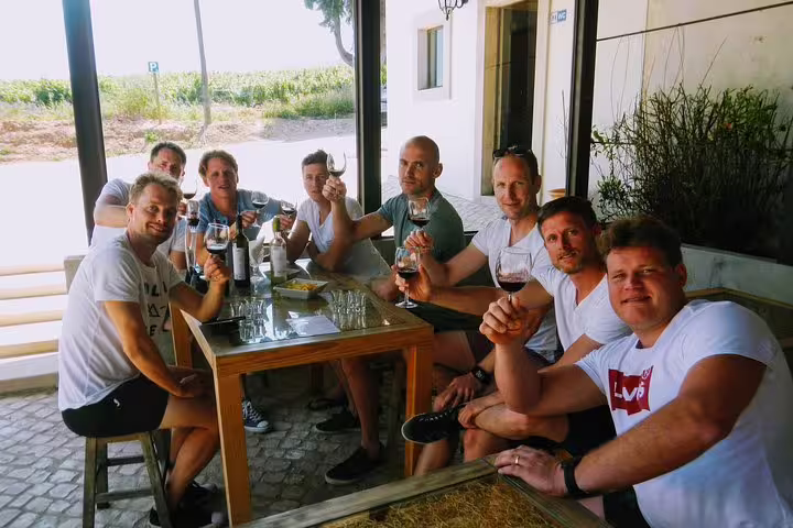 Group enjoying wine tasting at a vineyard on Lisbon's scenic south coast, highlighting wine tourism and cultural experiences.